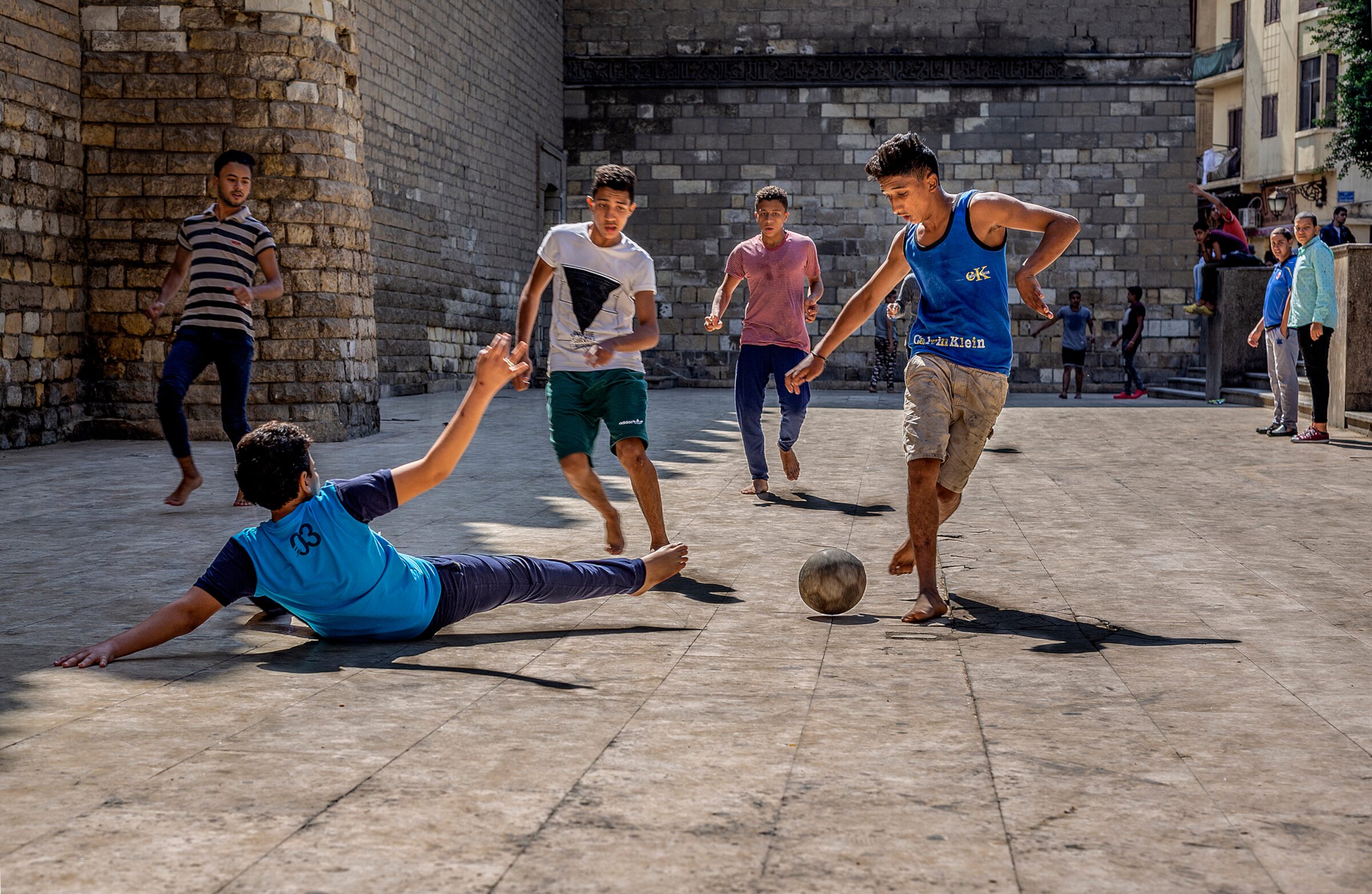 Children playing street football in a Cairo lane at dusk
